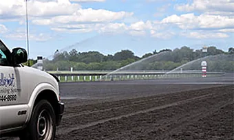 A service truck beside a horse arena being watered for dust control