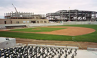 A ballpark under construction: the infield graded and turfed, seating standards set on the deck in the foreground