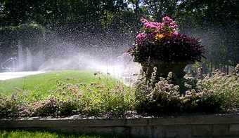Spray irrigation running over a planted bed and stone wall